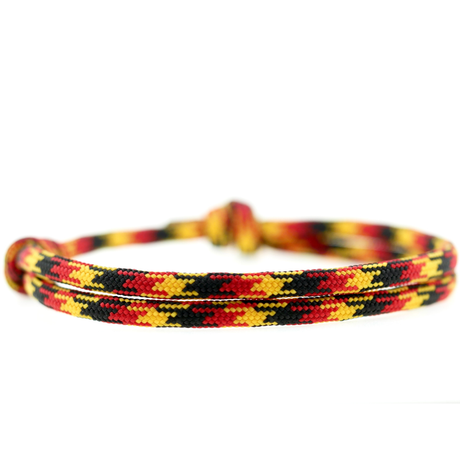 Surferarmband in Schwarz, Rot und Gold im minimalistischen Deutschland-Fan-Design auf hellem Hintergrund.